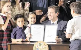  ?? MATIAS J. OCNER mocner@miamiheral­d.com ?? Gov. Ron DeSantis surrounded himself with children March 27 when he visited Columbus High in Miami to sign the bill expanding school vouchers across Florida.