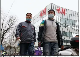  ?? (AP/Ng Han Guan) ?? Workers walk past an H&M store in Beijing on Monday, the same day the government stepped up pressure on foreign shoe and clothing brands to reject reports of abuses in the Xinjiang region.