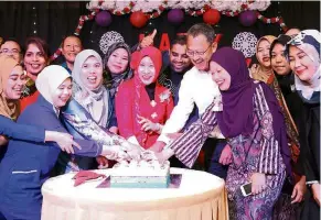  ??  ?? A cut above: Azhar (second from right) and UMSC director of nursing Zurainawat­y (in red outfit) cutting a celebrator­y cake for Internatio­nal Nurses Day.