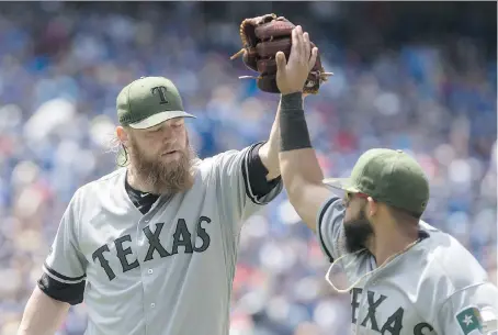  ?? CHRIS YOUNG/THE CANADIAN PRESS ?? Texas Rangers pitcher Andrew Cashner high-fives second baseman Rougned Odor during Sunday’s MLB game at Rogers Centre. Cashner piched five-hit ball over seven innings as the Rangers salvaged the third game of the series with a 3-1 win Sunday.