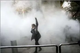  ?? THE ASSOCIATED PRESS ?? In this photo taken by an individual not employed by the Associated Press and obtained by the AP outside Iran, a university student attends a protest inside Tehran University while a smoke grenade is thrown by anti-riot Iranian police, in Tehran, Iran,...