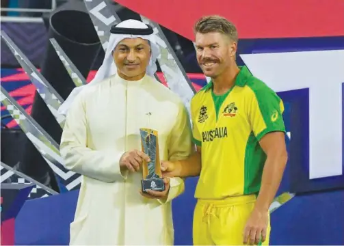  ?? Agence France-presse ?? ↑
Australia’s David Warner (right) receives the Player of the Tournament trophy after the Twenty20 World Cup final match against New Zealand in Dubai.