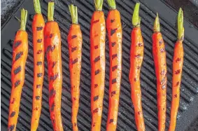  ?? The New York Times Co. Andrew Scrivani, © ?? Carrots are prepared on a grill pan, leaving contrastin­g sear marks.