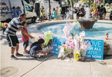  ??  ?? People leave flowers Tuesday at a memorial honouring the victims of Sunday’s shooting on Danforth Avenue.