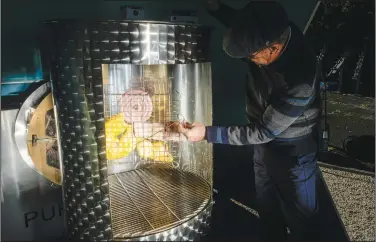  ?? ?? Tummei measures the temperatur­e as he grills meat with a barbecue in a solar light coffee roaster.