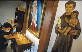  ?? Photograph­s by Brian van der Brug Los Angeles Times ?? NIKKO Yeressian, 8, lights a candle prior to Sunday services at Our Lady Queen of Martyrs Church, once deemed the center of Catholic Armenian life in L.A.