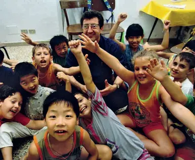  ??  ?? Don Momigli qualche anno fa insieme ai bambini di San Donnino (foto: Sestini)