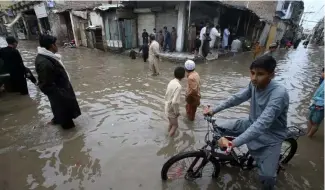  ?? ?? Youngsters wade through a flooded street caused by heavy rain in Peshawar, Pakistan in April