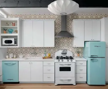  ??  ?? ABOVE, LEFT: CHRISTINE BALANCED THE WHITE KITCHEN WITH ROBIN’S EGG- BLUE APPLIANCES FROM ELMIRA STOVE WORKS. “THE CLASSIC WHITE SLAB CABINETS ALLOW THE APPLIANCES TO BE THE STAR OF THE SHOW,” SAYS MICHAEL. THEIR RETRO BLUE COLOR AND STYLE COMPLEMENT THE CUSTOM BACKSPLASH TILES. “THE TILE COLORS ARE INSPIRED BY THE ICONIC GEORGE NELSON BALL CLOCK,” SAYS CHRISTINE. “IT WAS A TILE IN BLACK AND WHITE, AND I WAS ABLE TO CUSTOMIZE TWO OF THE COLORS.”
ABOVE, RIGHT: THE BEDROOM CAN SERVE AS A PLACE TO REST OR A PLACE TO WORK. WITH A FUNCTIONAL DESK AGAINST THE WALL AND A DAYBED FROM KARDIEL, THIS VERSATILE SPACE CAN BE USED FOR ANY NEED. THE MATTHEWS FAN COMPANY CEILING FAN KEEPS THE ROOM COOL, AND THE SLIDING GLASS DOORS AND CLERESTORY WINDOWS ALLOW IN PLENTY OF NATURAL LIGHT.