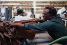  ??  ?? An employee of the Courteney boot company selects leather that will be used to make shoes.