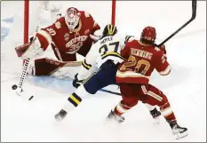  ?? Michael Dwyer / Associated Press ?? Denver goalie Magnus Chrona blocks a shot by Michigan’s Nolan Moyle during the second period of Thursday’s Frozen Four semifinal game in Boston.