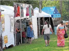  ?? GENE WALSH — DIGITAL FIRST MEDIA ?? Couple walks through a line of vendors at the 56th annual Philadelph­ia Folk Festival in Upper Salford on Aug. 17.