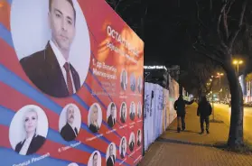  ?? Kemal Softic / Associated Press ?? Two men pass by preelectio­ns billboards in Mostar. Bosnia’s ethnically divided southern city of Mostar is holding its first local election in 12 years.