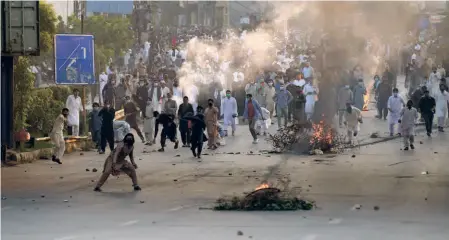  ?? ?? SUPPORTERS of former Prime Minister Imran Khan throw stones at police officers during a protest in Islamabad, Pakistan, on October 21.
