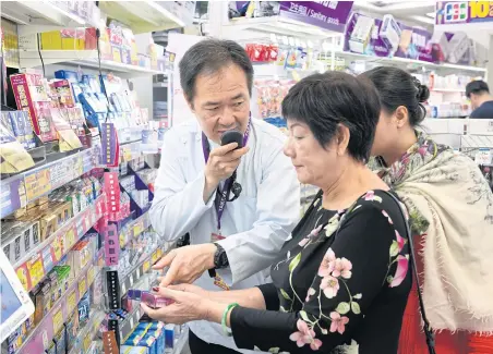  ?? PHOTOS BY BLOOMBERG ?? A shop assistant, left, assists a customer with a Sourcenext Corp’s Pocketalk portable translatio­n device in Tokyo.