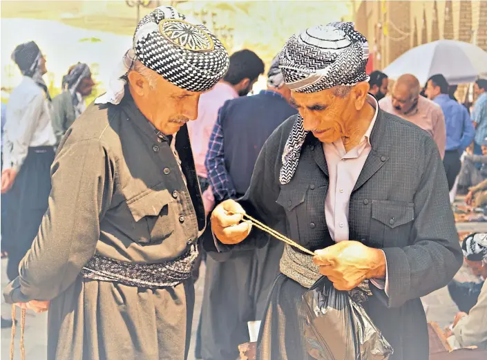  ??  ?? COMMERCE: Two Kurds deep in conversati­on in one of Erbil’s thronging markets