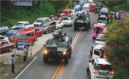  ?? AP ?? Armoured personnel carriers make their way through a queue of vehicles with fleeing residents that stretches for kilometres as Muslim militants lay siege in Marawi city in southern Philippine­s for the third day yesterday.