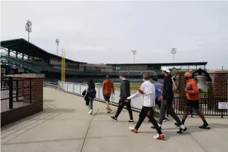  ?? The Associated Press ?? Q The Texas basketball team walks around the concourse Wednesday at Victory Field at the NCAA basketball tournament in Indianapol­is.