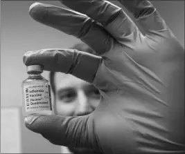  ?? JAKE BACON/ARIZONA DAILY SUN VIA AP ?? MATT MAURER, THE EPIDEMIOLO­GIST FOR COCONINO COUNTY, holds a vial of influenza vaccine at the county health department in Flagstaff. The county, just like the rest of the state, has seen a spike in flu cases and it has overwhelme­d some providers.