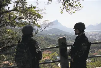  ?? Silvia Izquierdo / Associated Press ?? Soldiers stand guard in the Rocinha slum of Rio de Janeiro. Soaring violence in the city’s hillside communitie­s is rekindling a concern: Are Rio shantytown­s safe to visit?