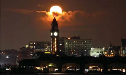  ?? ?? The 99% ‘beaver moon’ behind the Lackawanna clock tower in Hoboken, New Jersey. Photograph: Gary Hershorn/Getty Images