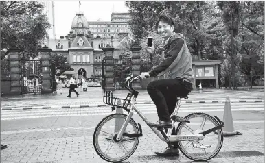  ?? HUA YI / XINHUA ?? A local resident in Sapporo, northern Japan, rides an orange and silver bicycle by Chinese bike-sharing company Mobike.