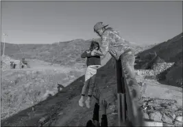  ?? ASSOCIATED PRESS ?? a migrant from Honduras passes a child to her father after he jumped the border fence to get into the U.S. side to San Diego, Calif., from Tijuana, Mexico.