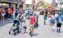  ?? PATRICK CONNOLLY/ORLANDO SENTINEL ?? Visitors wearing masks tour Hogsmeade at The Wizarding World of Harry Potter in Universal’s Islands of Adventure at Friday’s reopening.