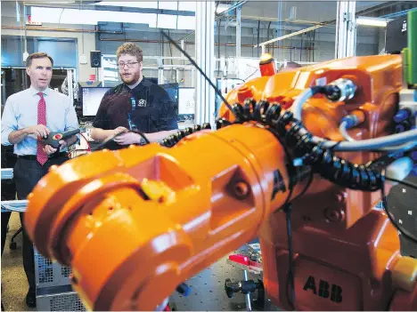  ?? TODD KOROL/THE CANADIAN PRESS FILES ?? Finance Minister Bill Morneau, left, operates a robot with a student during his tour of the robotics lab at the Southern Alberta Institute of Technology in Calgary last month. The Bank of Canada’s Carolyn Wilkins says technology has led to job opportunit­ies.