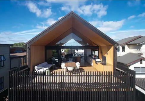  ??  ?? ABOVE Beneath the pitched roof, Metro Series joinery from First Windows & Doors surrounds a triangular window that offers an uninterrup­ted sight line through to the Port of Tauranga in the distance. OPPOSITE Custom-made shelving surrounds the fireplace in the living area, where furniture and lighting by Tim Webber Design creates a conversati­onal zone.