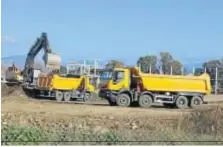  ??  ?? Una maquina excavadora carga tierra en un par de camiones.