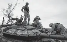  ?? Leo Correa/Associated Press ?? Ukrainian servicemen stand atop a destroyed Russian tank in a retaken area near the border with Russia.