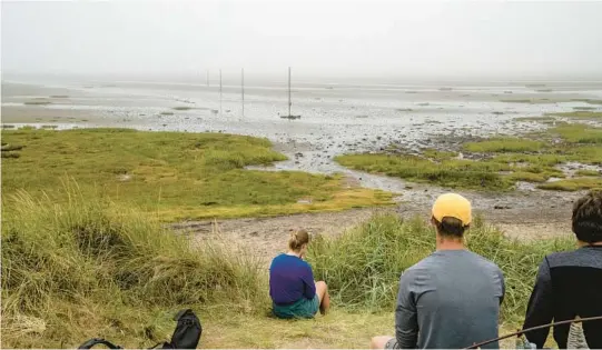  ?? ANDREW TESTA/THE NEW YORK TIMES PHOTOS ?? A group rests in August after walking across the causeway at low tide from northern mainland England to Holy Island.