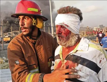  ??  ?? Carnage: A firefighte­r leads a man to safety as the city burns around them