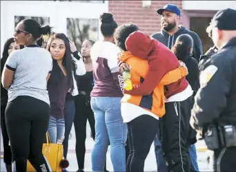  ?? Stephanie Strasburg/Post-Gazette ?? People embrace at a vigil for 16-year-old Deven Holloway, a sophomore at Penn Hills High School, outside of Linton Middle School on Wednesday in Penn Hills.