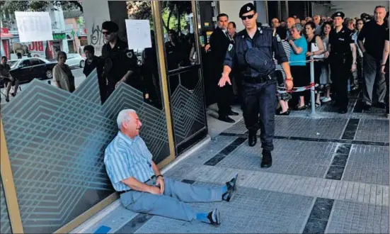  ?? SAKIS MITROLIDIS / AFP ?? Un jubilat plora a les portes d’un banc perquè només pot treure 120 euros de la seva pensió a Salònica, Grècia