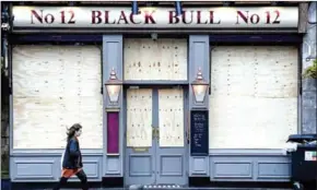  ?? AFP ?? A pedestrian walks past a closed pub in Glasgow as govt orders two-week closure.