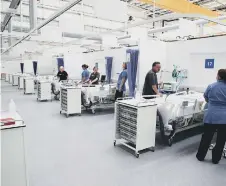  ??  ?? Staff preparing bays at the NHS Nightingal­e hospital d. PA Photo.