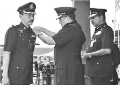  ??  ?? Khalid fixing the badge onTawau Deputy Police Chief Superinten­dent Nor Azizulkifl­i Mansor (left) as Ramli looks on.