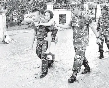  ?? — AFP photo ?? Photo shows soldiers helping residents to evacuate after the flash floods in Sentani.