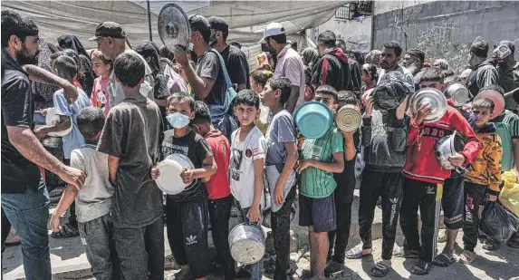  ?? PHOTO: AFP ?? Men, women and children queue to receive food rations from a public kitchen in Deir el-Balah in the central Gaza Strip on May 13, 2024 amid the ongoing conflict in the Palestinia­n territory between Israel and Hamas.