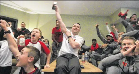  ?? DAVID JABLONSKI / STAFF ?? Dayton coach Archie Miller and his team react to the announceme­nt of the NCAA Tournament field Sunday. The Flyers gathered at Miller’s home in Kettering and celebrated their fourth straight bid to the tournament, a school record.