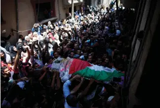  ?? (Mohammed Salem/Reuters) ?? MOURNERS CARRY the body of Palestinia­n paramedic Razan al-Najjar during her funeral in Khan Younis yesterday.