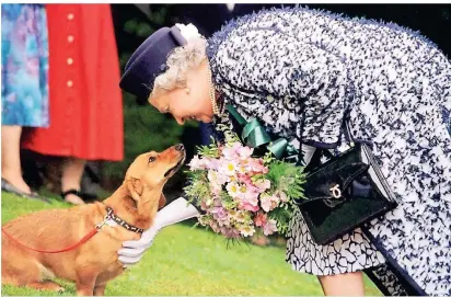  ?? FOTO: DPA ?? Die britische Königin Elizabeth II. streichelt 1998 einen ihrer Corgi-hunde.