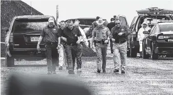  ?? AP PHOTO/DANNY ZARAGOZA ?? Law enforcemen­t officers gather near the scene where the body of a woman was found near Interstate 35 north of Laredo, Texas, on Saturday. A U.S. Border Patrol agent suspected of killing four women was arrested early Saturday after a fifth woman who had been abducted managed to escape from him and notify authoritie­s, law enforcemen­t officials said, describing the agent as a “serial killer.”
