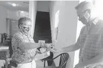  ?? JOE CAVARETTA/SOUTH FLORIDA SUN SENTINEL ?? Peggy Brereton offers hand sanitizer to Joe Huck before services Sunday at the Sunshine Cathedral in Fort Lauderdale.