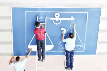  ??  ?? Workers remove the Barisan Nasional logo from a wall at the PBB headquarte­rs following Abang Johari’s announceme­nt.