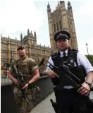  ??  ?? A soldier and police officer walk past the Houses of Parliament in London