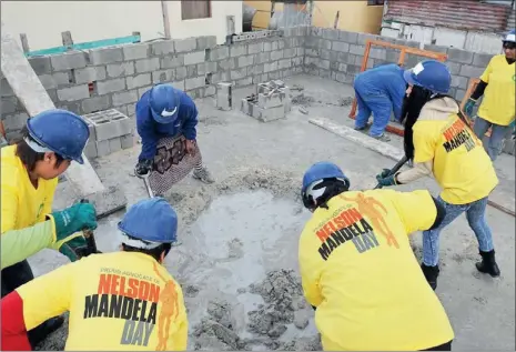  ?? PICTURE: DAVID RITCHIE ?? GETTING STUCK IN: Mandela Day volunteers help build homes in Mfuleni last year for beneficiar­ies of the Habitat for Humanity project.