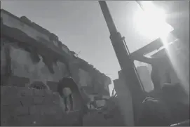  ?? Associated Press ?? n A man climbs rubble from an airstrike Wednesday on a hotel in Arhab, Yemen, in this image taken from video. A Saudi-led coalition carried out several airstrikes in Yemen early on Wednesday, hitting a small hotel near the capital of Sanaa and killing...
